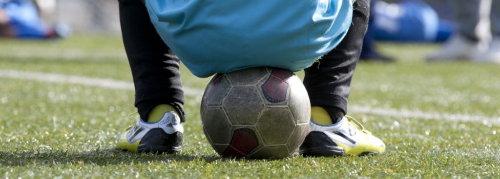 Niño sentado en un balón durante entrenamientos Niño sentado en un balón durante entrenamientos